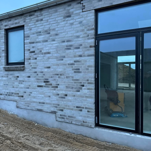 Nybyg i Skanderborg med store glaspartier og detaljeret murstensfacade.