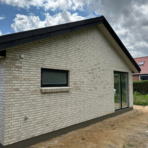 Nybyggeri i Silkeborg med lyse mursten og sort tagfod under blå himmel.