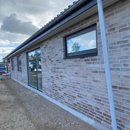 Lang facade på nybyggeri i Aarhus med moderne mursten og tagrender.